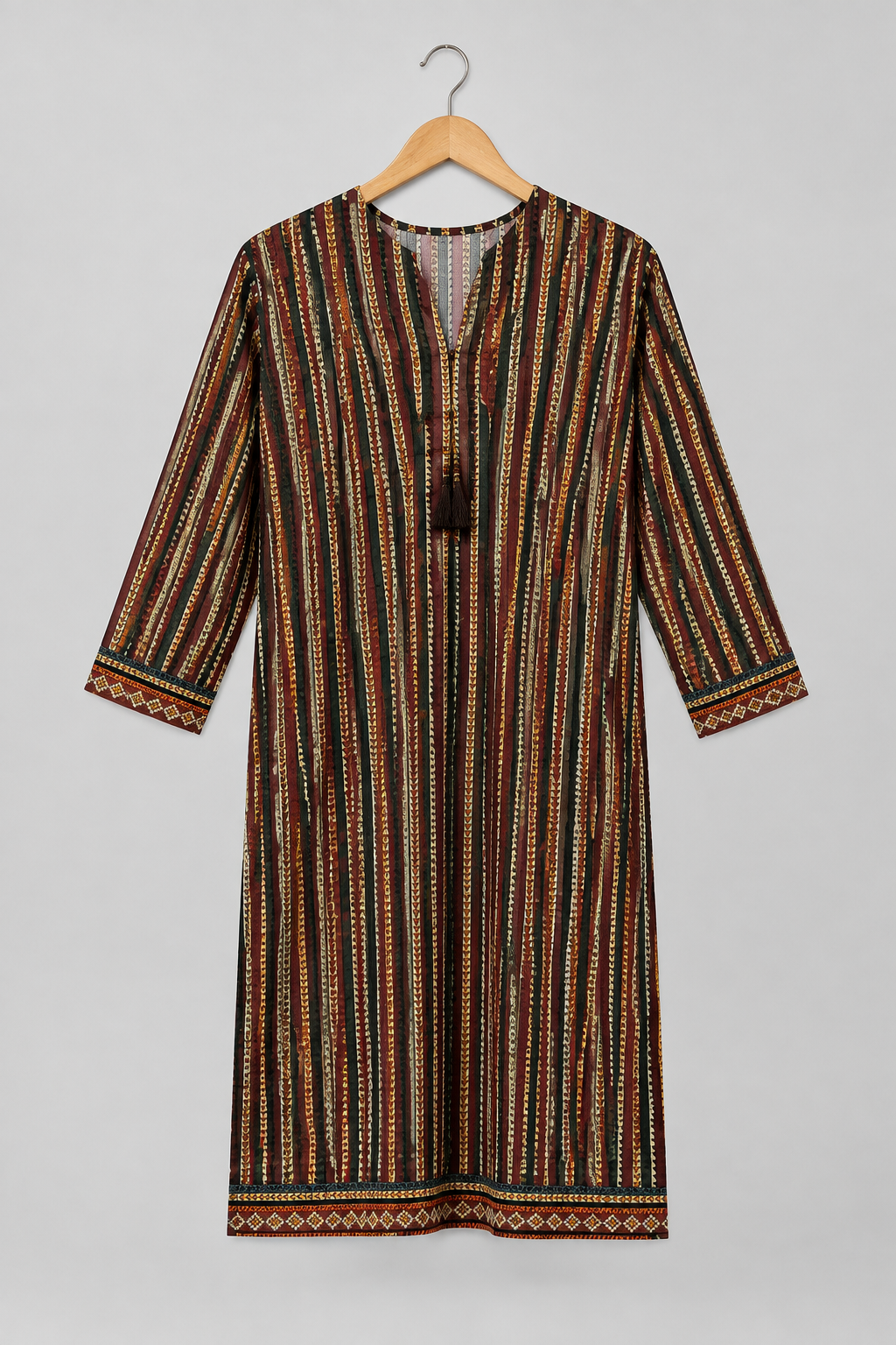 A long-sleeve tunic dress with a vertical striped pattern in brown, black, orange, and cream, hanging on a wooden hanger against a light gray background.