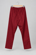 A pair of loose-fitting, cropped red pants with an elastic waistband and wide legs, hanging on a metal hanger against a white wardrobe door.