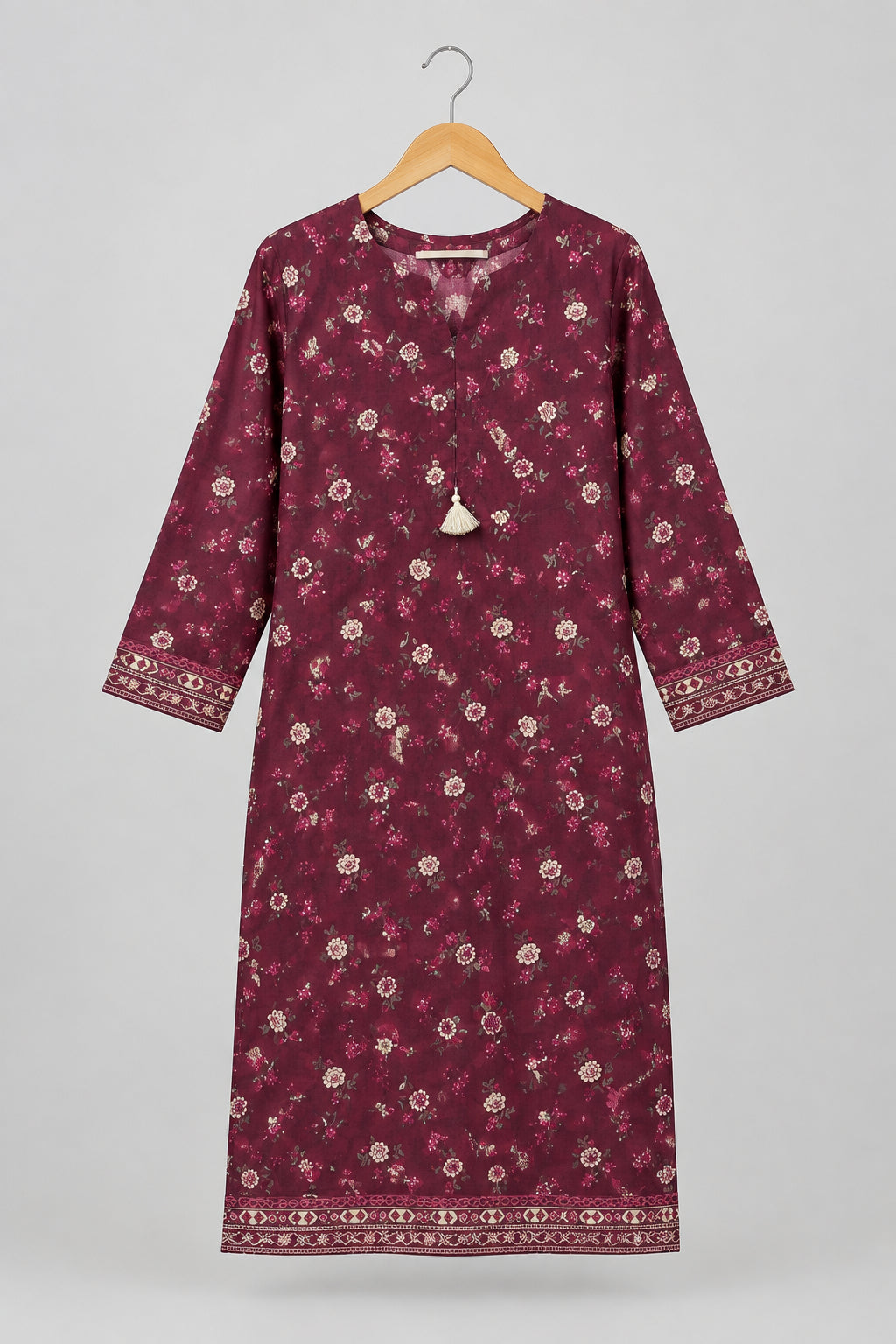 A long-sleeved maroon kurta with a small white floral print, hanging on a metal hanger against a white wardrobe door.