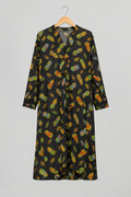 A black long-sleeve tunic or robe with a colorful all-over leaf print, hanging on a metal hanger against a white wardrobe door.