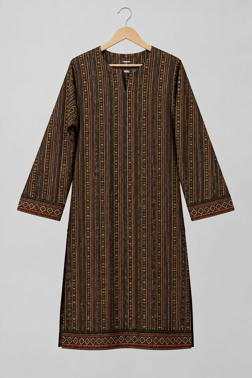 A long-sleeved tunic dress with vertical stripes in brown, black, and gold, hanging on a metal hanger against a white wardrobe door.