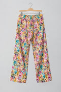 A pair of women's wide-leg pants with a vibrant multicolor floral print, hanging on a metal hanger against a white wardrobe door.