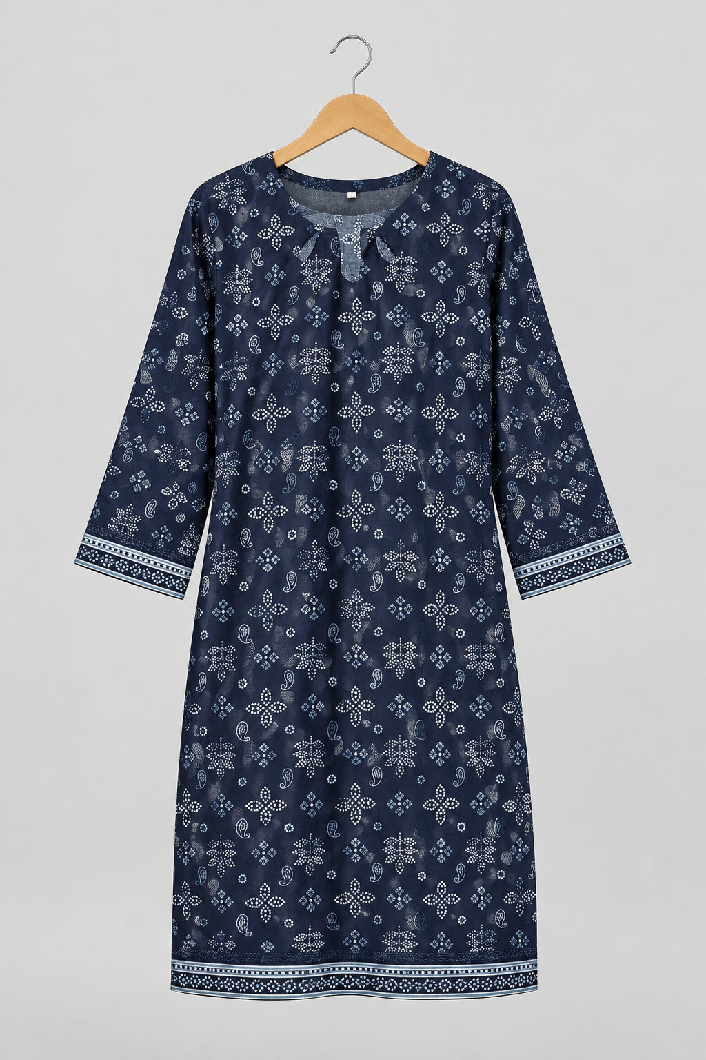 A long-sleeve tunic dress with a dark navy blue and white geometric pattern, hanging on a metal hanger against a white wardrobe door.