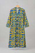 A blue and yellow patterned long-sleeve shirt dress hanging on a metal hanger against a white wardrobe door.