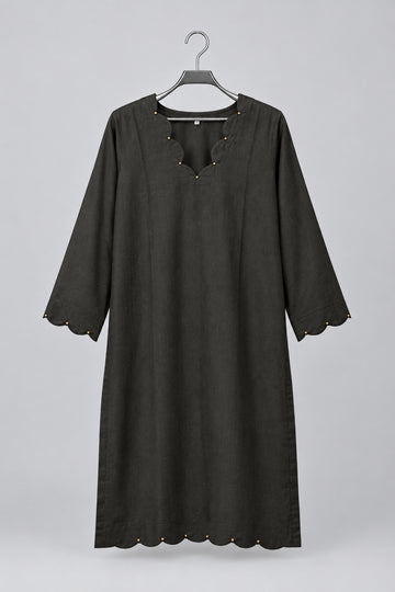 A black three-quarter sleeve tunic top with scalloped edges and decorative beadwork, hanging on a metal hanger against a white wardrobe door.