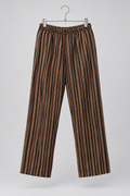 A pair of wide-leg trousers with vertical stripes in brown, beige, and black, hanging from a silver metal hanger against a light gray background.